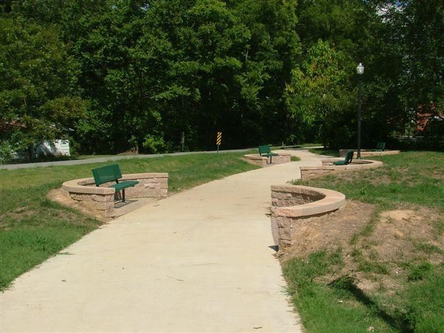 Downtown Trail Paved trail lined with benches leading to woods